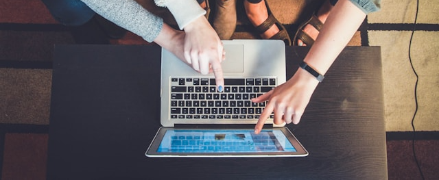 People Pointing at a Laptop Screen